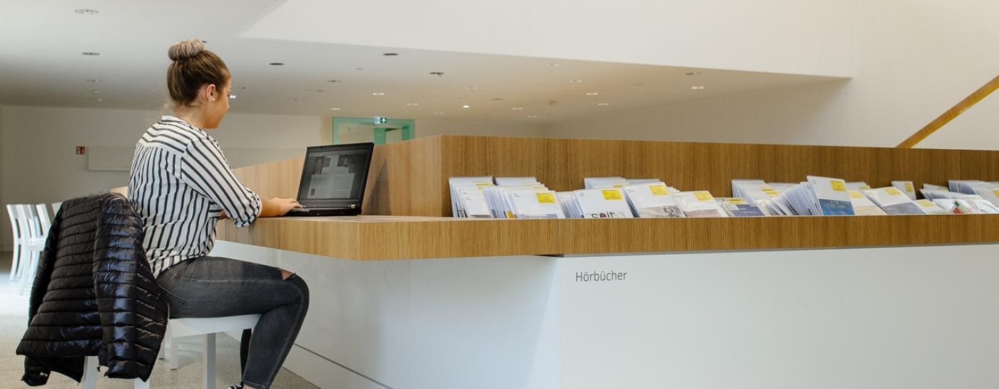 Mädchen sitzt vor Laptop in der Bibliothek Mädchen sitzt vor Laptop in der Bibliothek